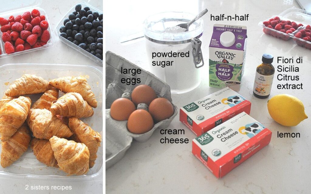 A basket with mini croissants, fresh berries, eggs, packages of cream cheese, and a lemon on the counter.