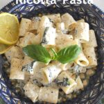 A blue plate filled with rigatoni pasta with a creamy ricotta sauce.