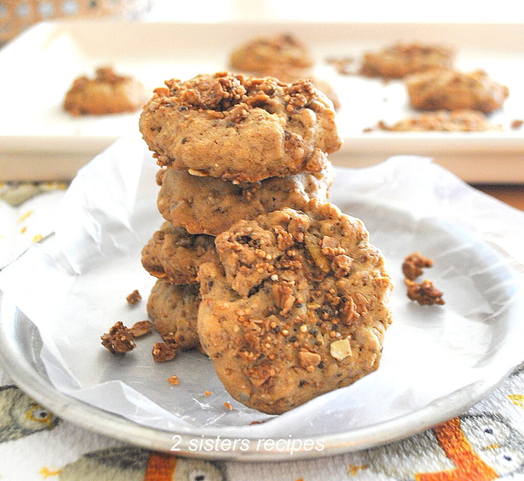 A dish with parchment paper and four granola cookies on top of one another.