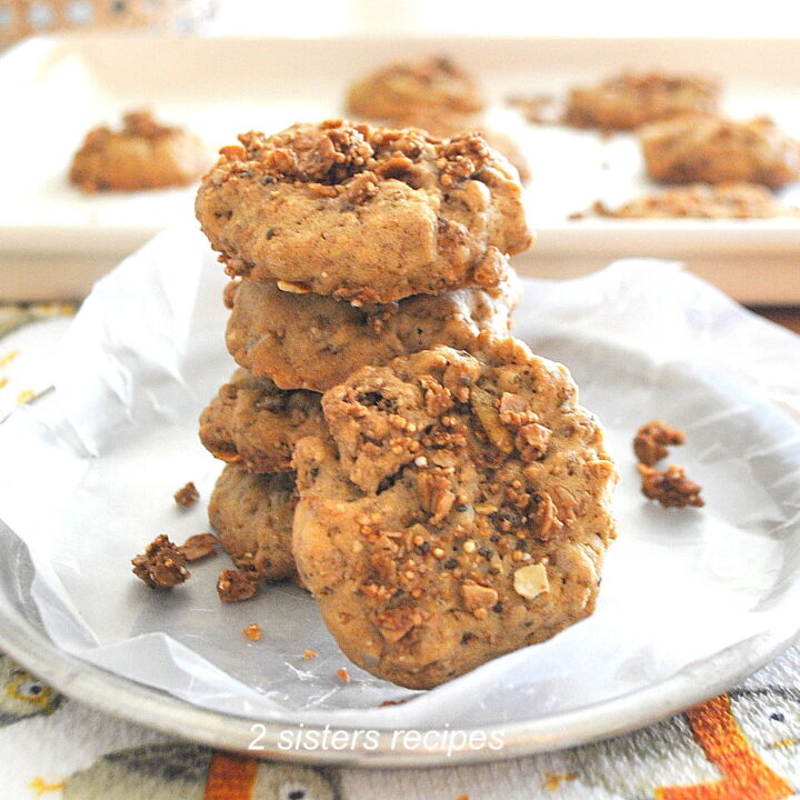 A dish with parchment paper and four granola cookies on top of one another.