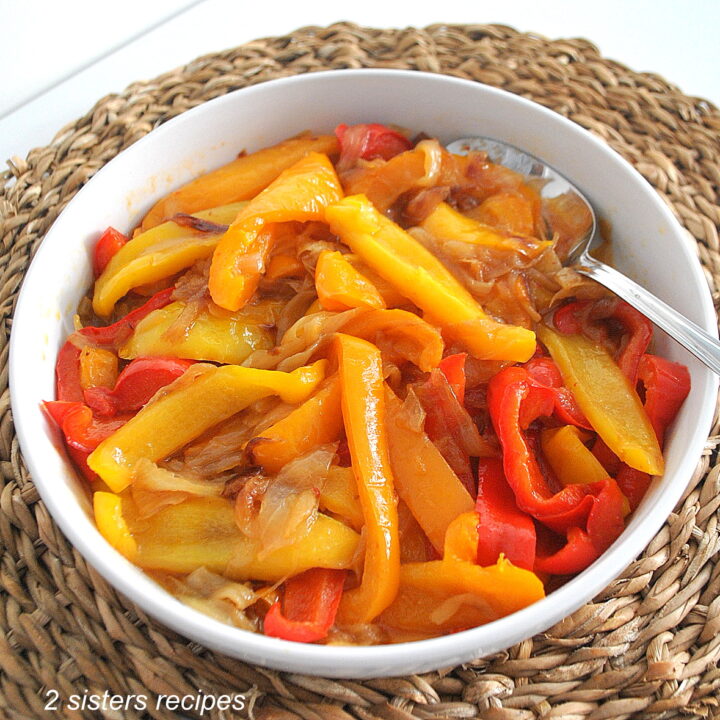 A white round bowl filled with sautéed colorful peppers and onions.
