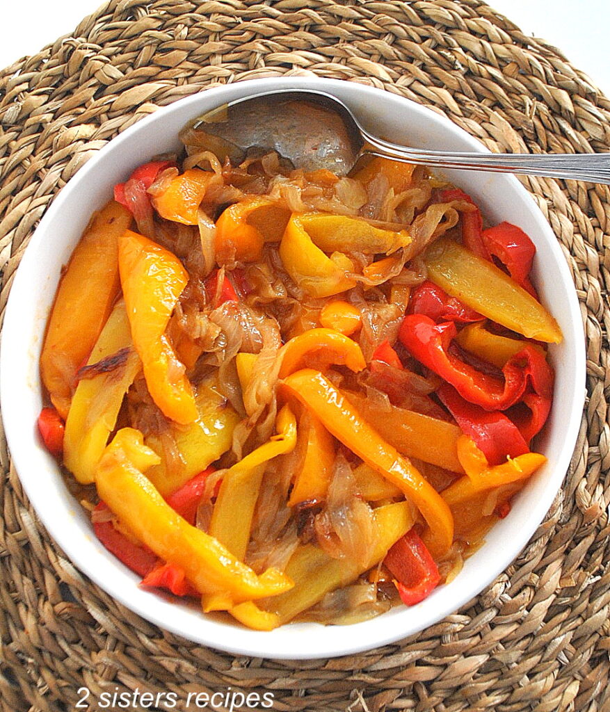 A white round bowl with sautéed peppers and onions. 