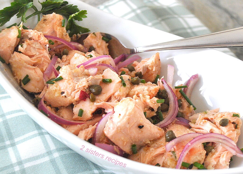 A oval serving dish filled with a cooked salmon salad with capers.