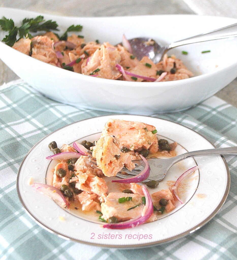 A plate with a serving of salmon salad with a fork. 