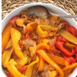 A white bowl filled with cooked peppers and onions.