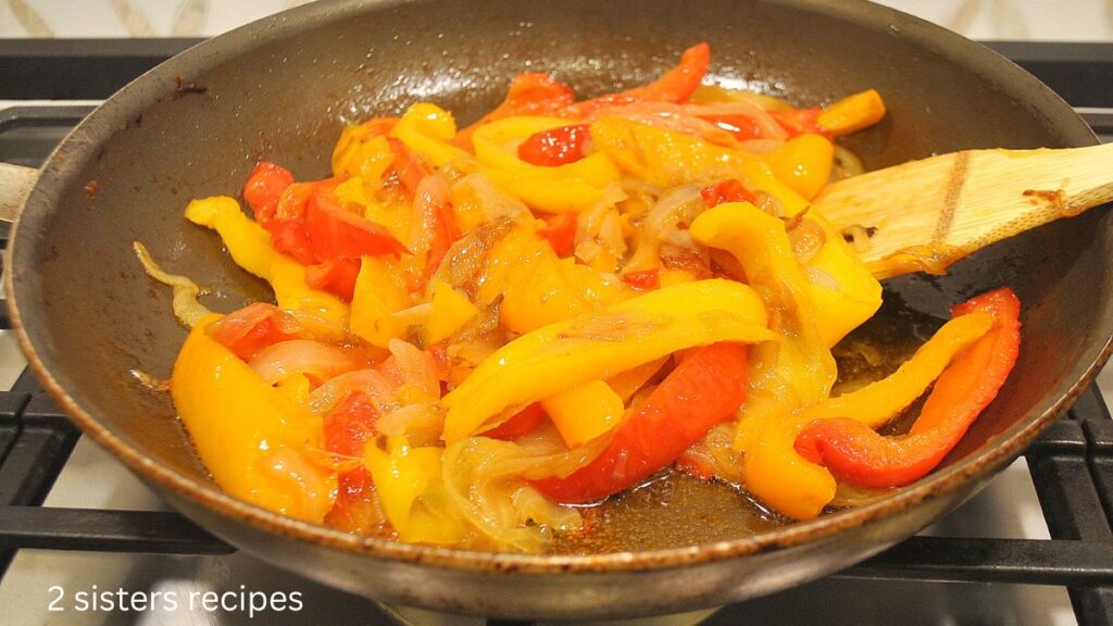 A large skillet filled with sautéed peppers and onions.