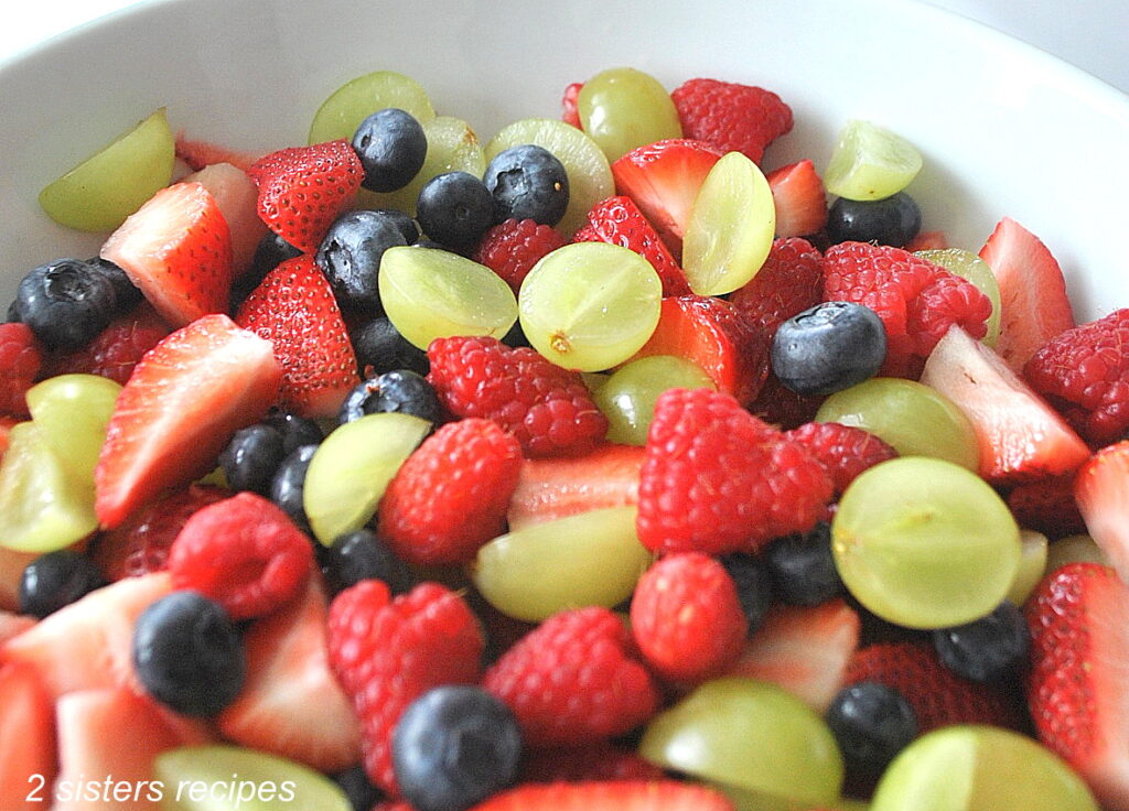 A mixture of cleaned fresh berries and grapes in a white bowl. 