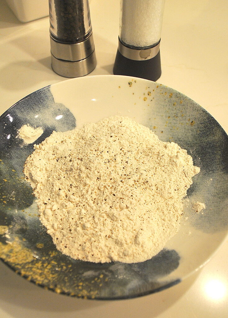 A blue and white shallow bowl filled with some flour.
