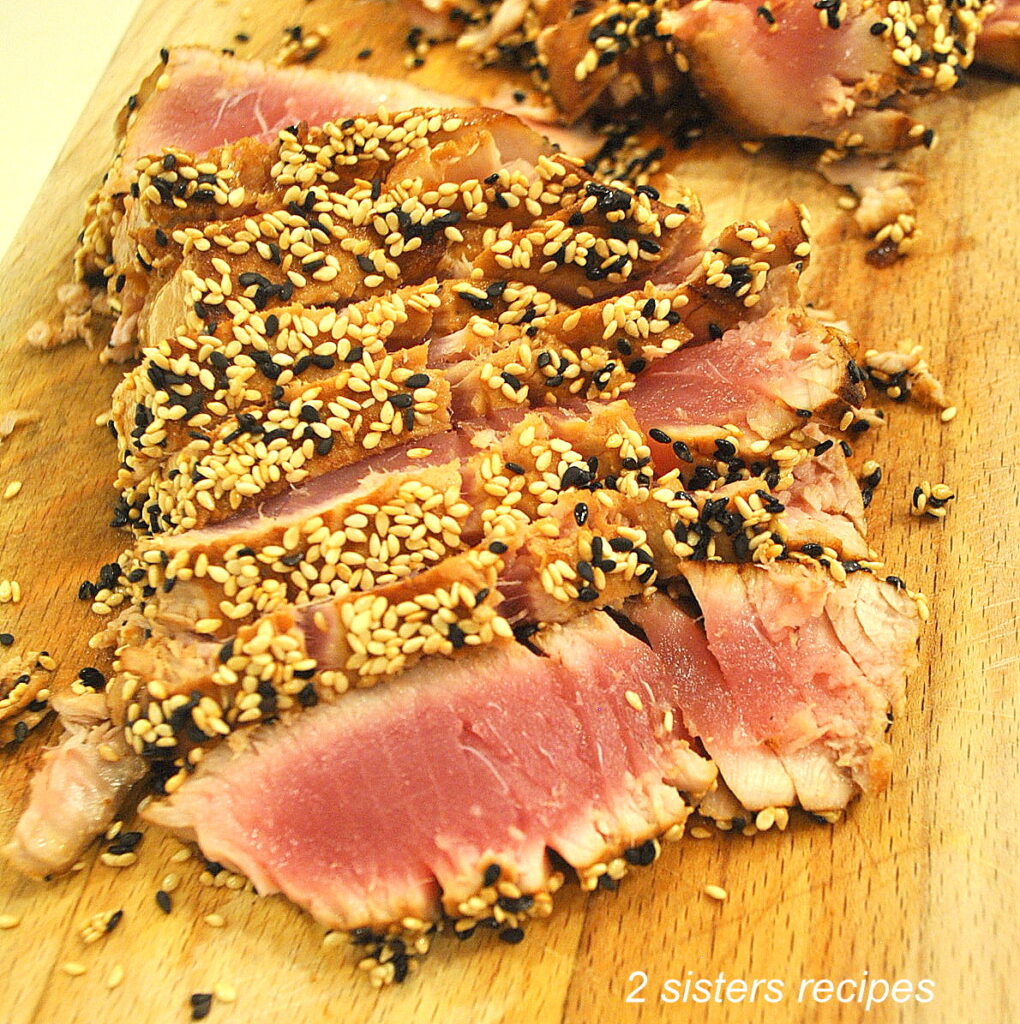 A cutting board with sliced seared sesame-crusted tuna. 