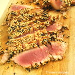 A cutting board with sliced seared sesame-crusted tuna.
