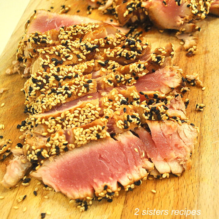 A cutting board with sliced seared sesame-crusted tuna.