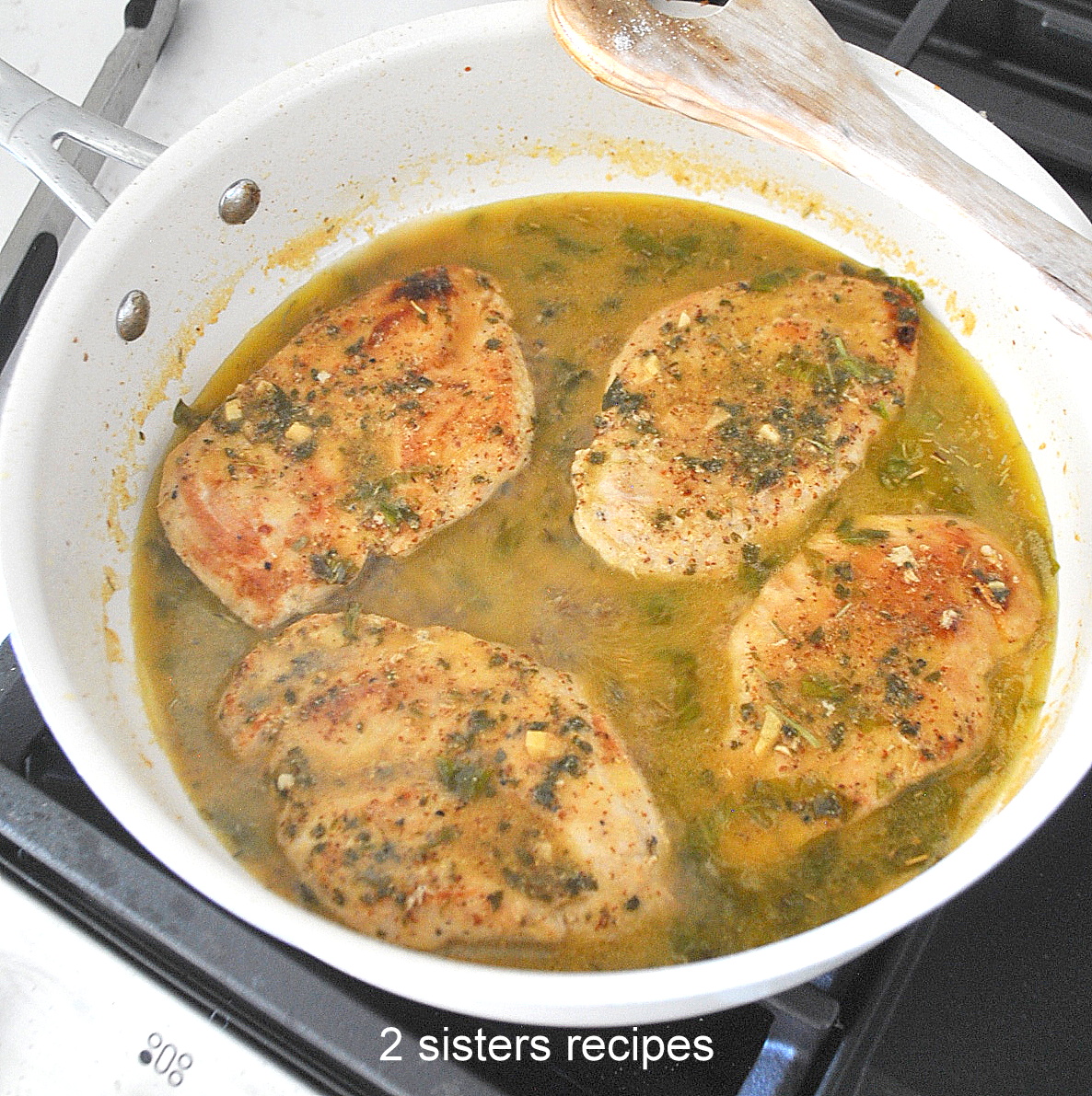 A white pan with cooked chicken with herb sauce. 
