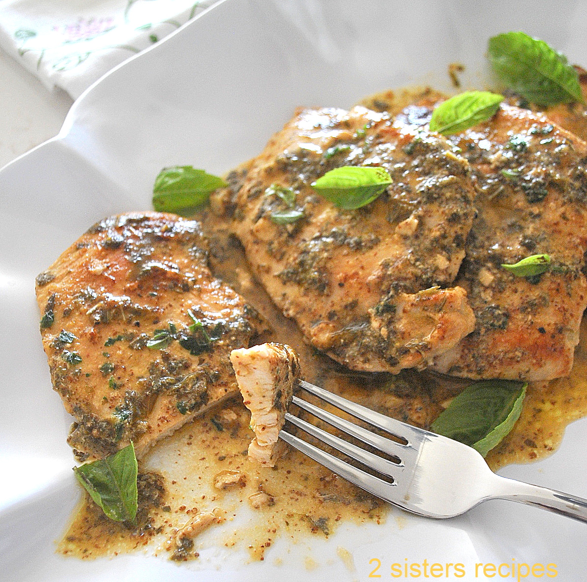 A forkful of cooked chicken cutlet smothered with mustard, and herb sauce.