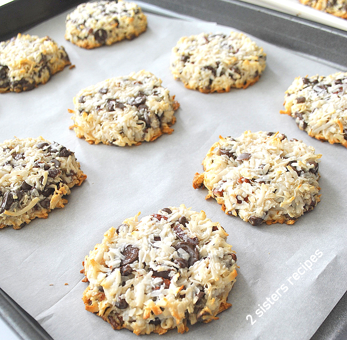 A baking sheet filled with baked coconut chocolate chip cookies.