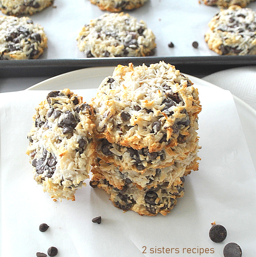 Coconut chocolate chip cookies piled on top of one another on a white dish.