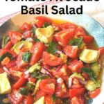 A blue and white bowl filled with a chilled tomato salad, with a spoonful of tomato, avocado and basil.