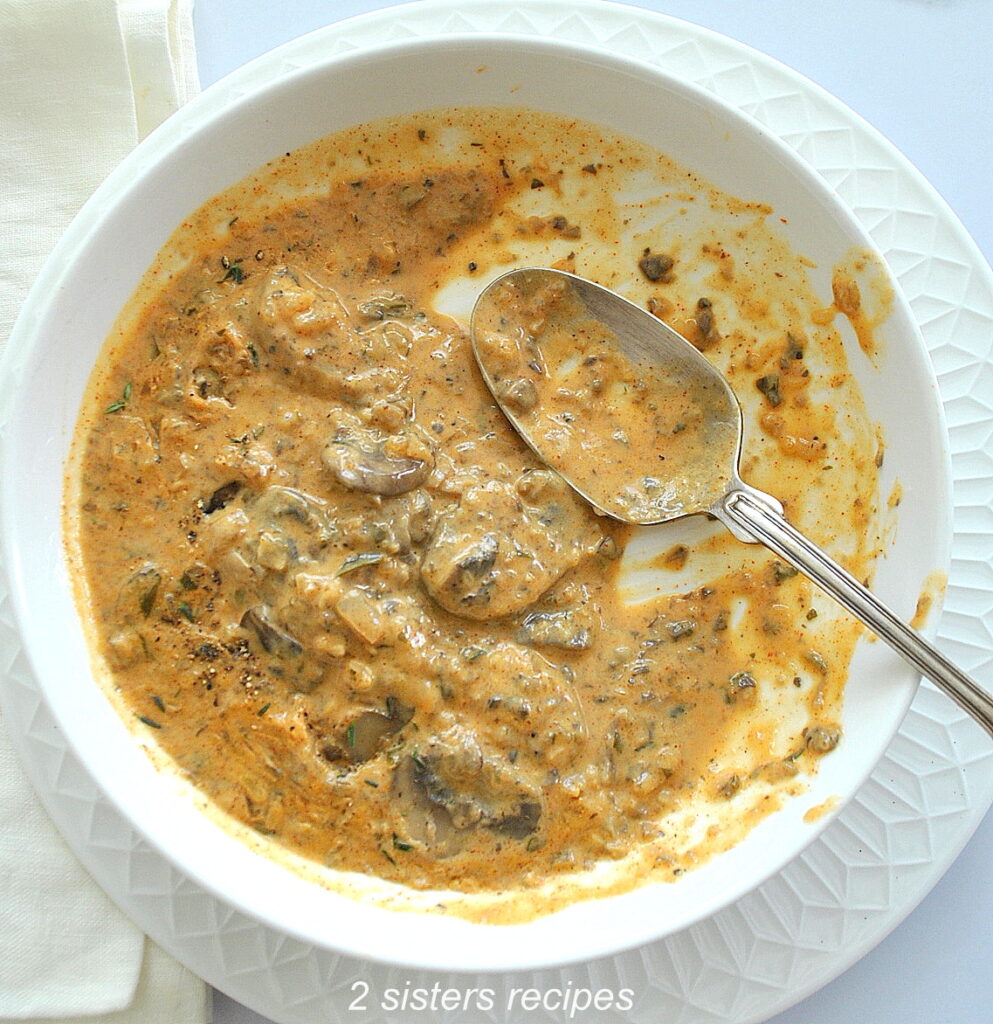 A bowl of mushroom soup with a spoon inside the dish. 
