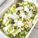 A rectangular serving bowl filled with a celery salad with cheese shavings on top.