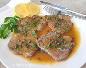 Four pieces of thin steak seared and served on a white plate with a lemon sauce.