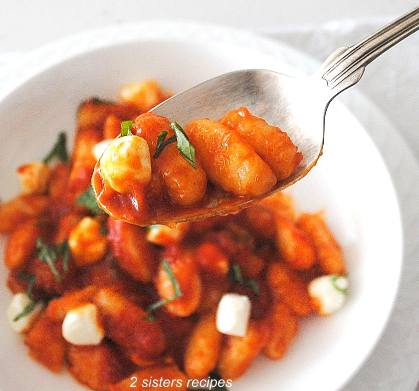 A spoonful of gnocchi with pearl of mozzarella and tomato sauce.