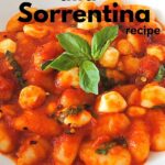 A white dish filled with gnocchi in tomato sauce with mozzarella balls and fresh basil on top.