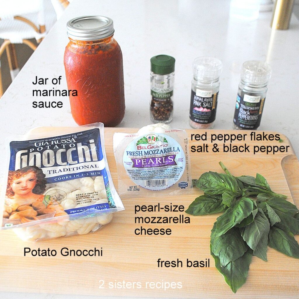 Ingredients placed on the wooden board, Package of Gnocchi, mozzarella balls, fresh basil and jar of tomato sauce.